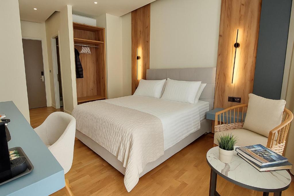 a bedroom with a bed and a table and a chair at Elite Patras Suites in Patra