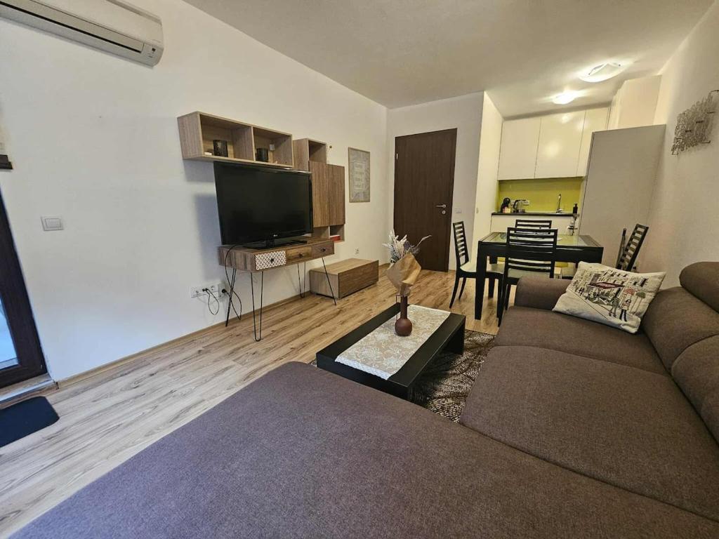 a living room with a couch and a tv and a table at Charming Apartment Borovets Gardens D16 in Samokov