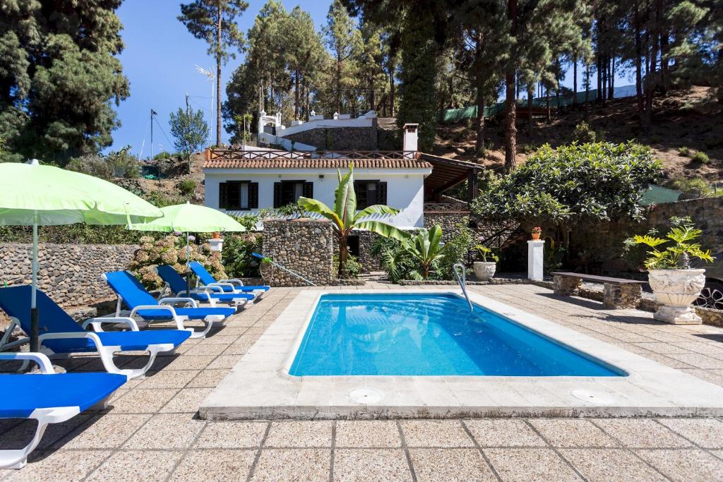 Una piscina con tumbonas y una casa. en Home2Book Icod Rural Escape Pool BBQ, en El Amparo