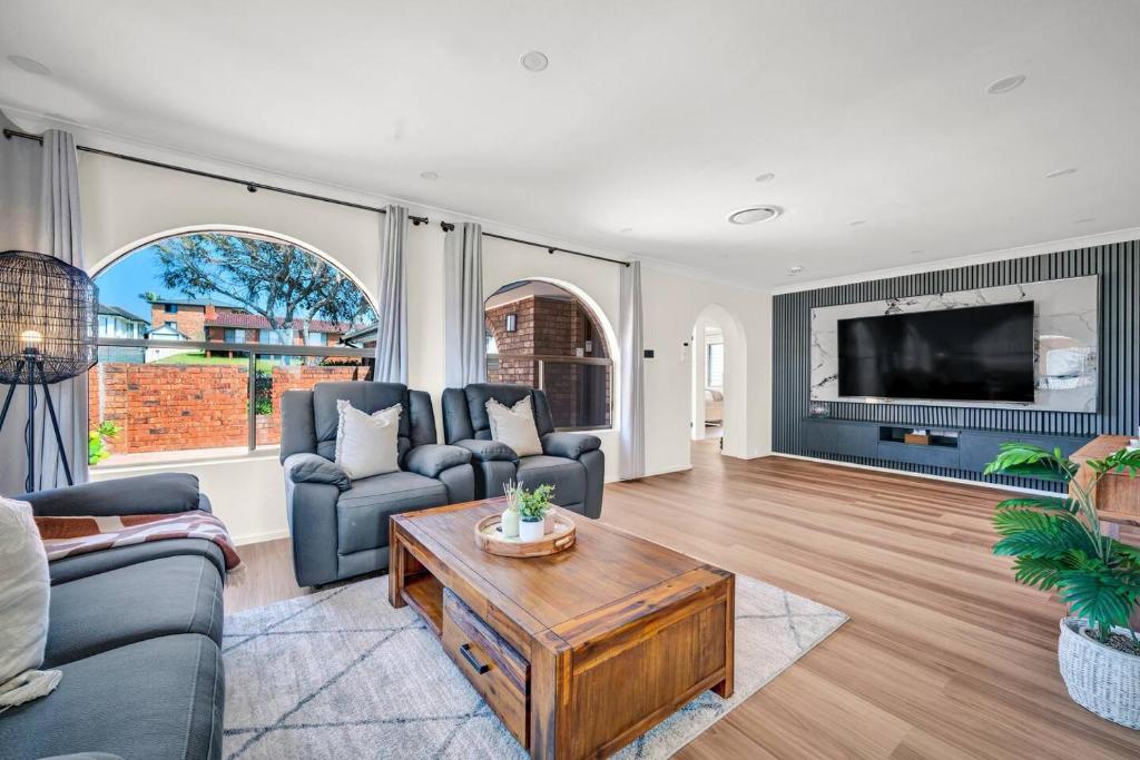a living room with a couch and a table at Sienna Arches - Modern Family Haven near Ocean Baths in The Entrance