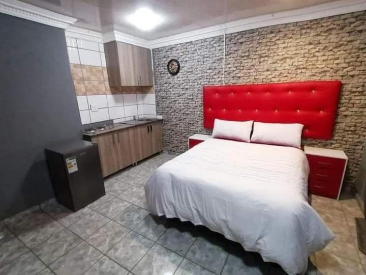 a bedroom with a large bed with a red headboard at Nice Luxury Homes in Nelspruit