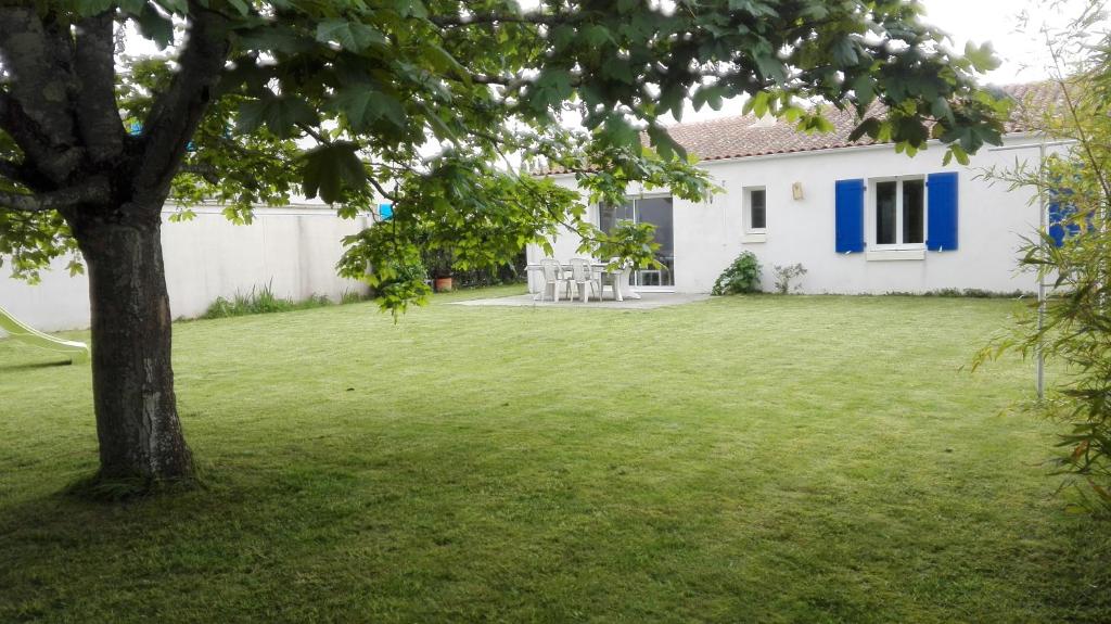 une cour avec une maison blanche et un arbre dans l'établissement Maison familiale idéale pour vacances, à Saint-Georges-dʼOléron