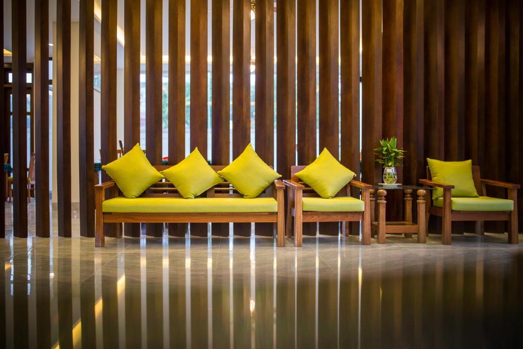 a couch with yellow pillows sitting in a room at Hoi An Green Apple Hotel in Hoi An