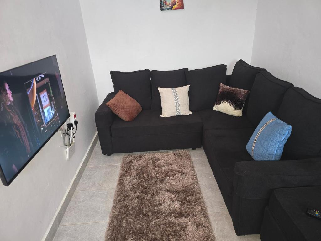 un sofá negro en una sala de estar con TV en SK CBD Suites airb Wundanyi Taita Taveta County, en Wundanyi