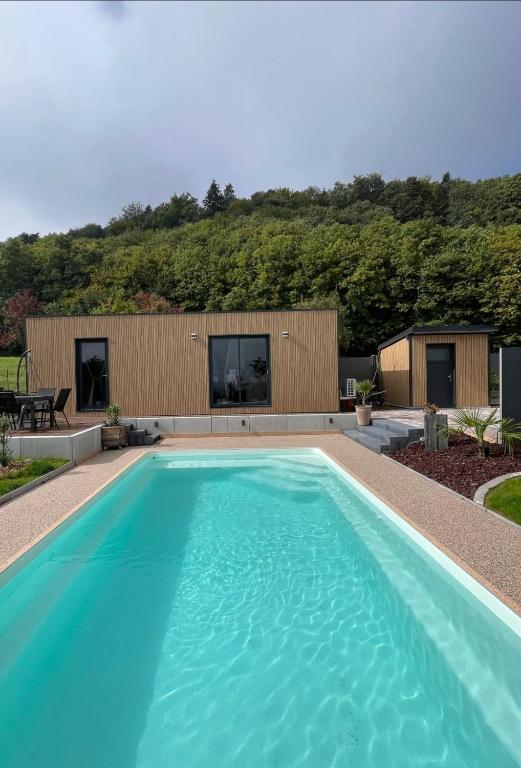 a swimming pool in front of a house at Les sources Caline in Haegen
