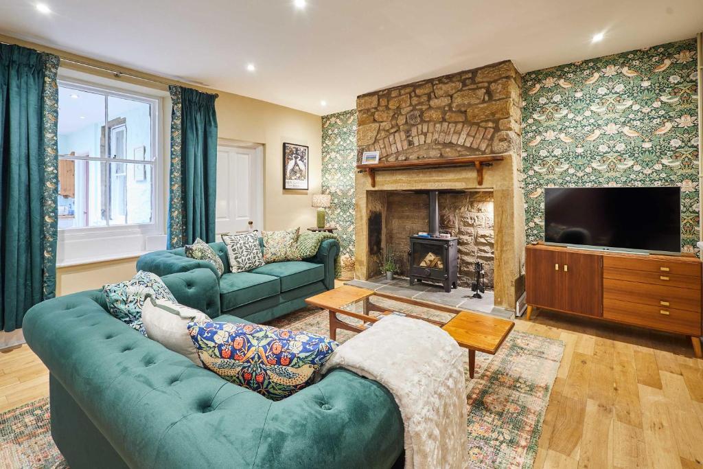 a living room with a green couch and a fireplace at Host & Stay - Sonsy Cottage in Alnmouth