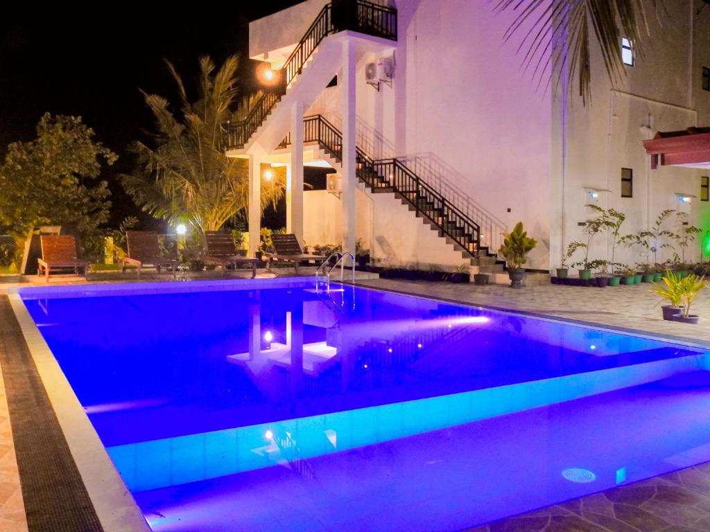 Una piscina frente a un edificio por la noche. en My Safari Resort, en Tissamaharama