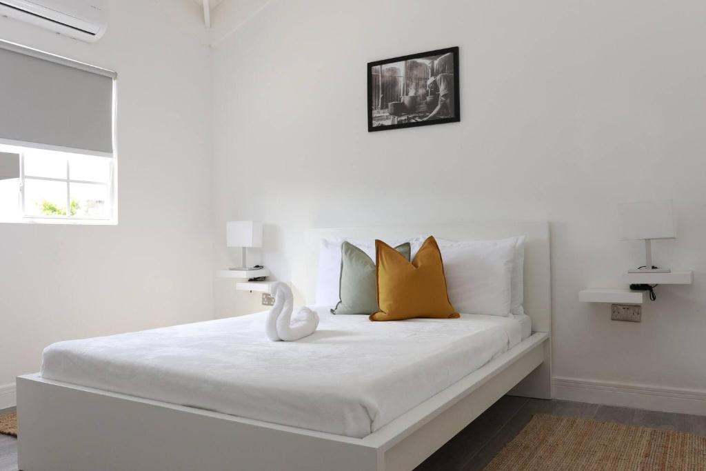 un lit blanc avec des oreillers jaunes et un oiseau blanc dessus dans l'établissement Eshae Living - Spacious 2BR with breakfast & pool, à Stanmore Grove