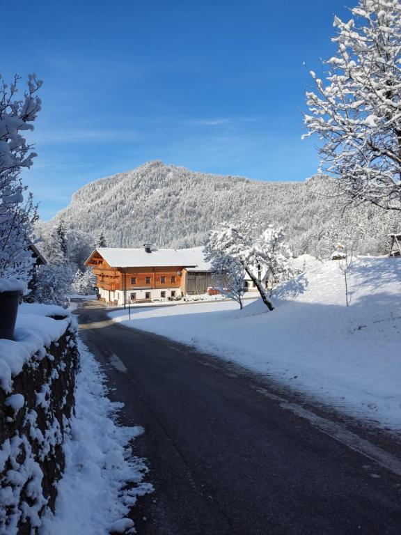 a house on a snow covered road next to a mountain at Ferienhaus Paulnhof Erl - Alpenglück für Gruppen, Freunde & Teams in Erlerberg