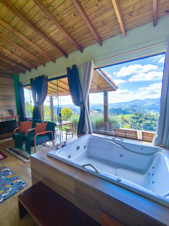 a large tub in a room with a large window at Chalé horizonte azul in Gonçalves