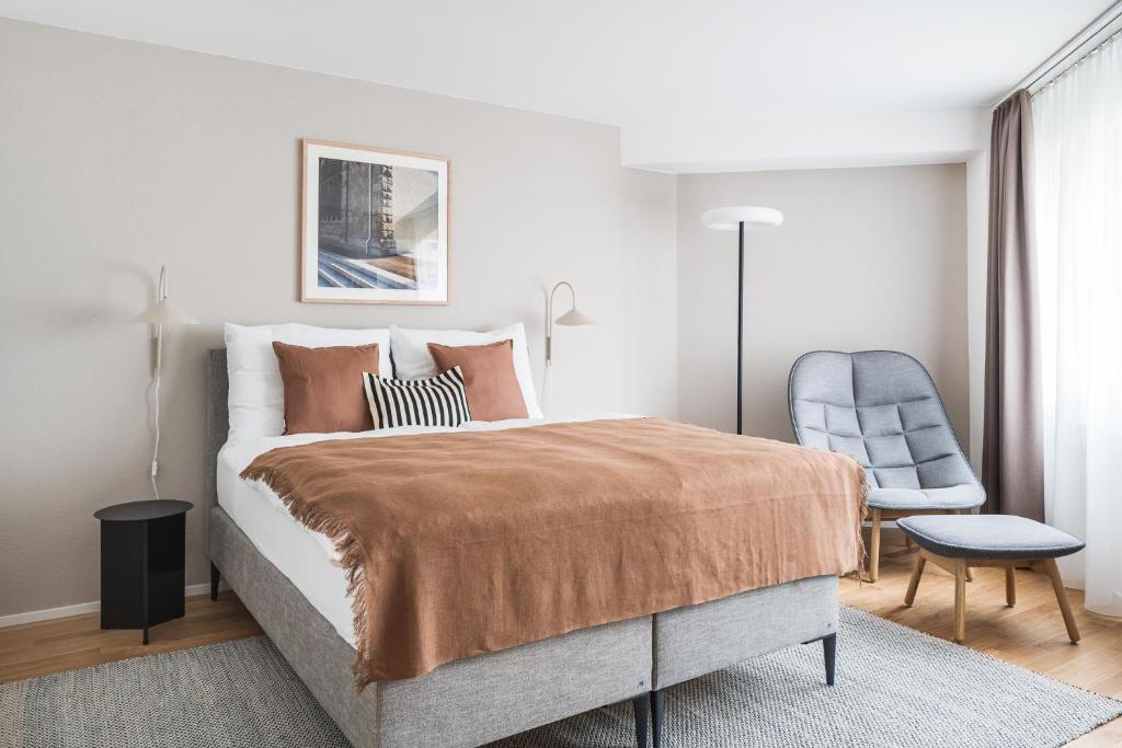 a bedroom with a large bed and a chair at PopUp - Stay3 self check in Apartments in Zürich