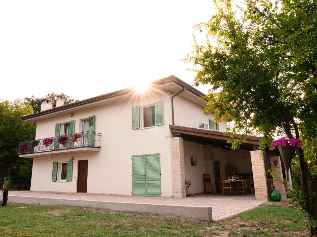a large white house with green doors and a patio at Podere Limeria Country Home nelle Marche in Fermignano