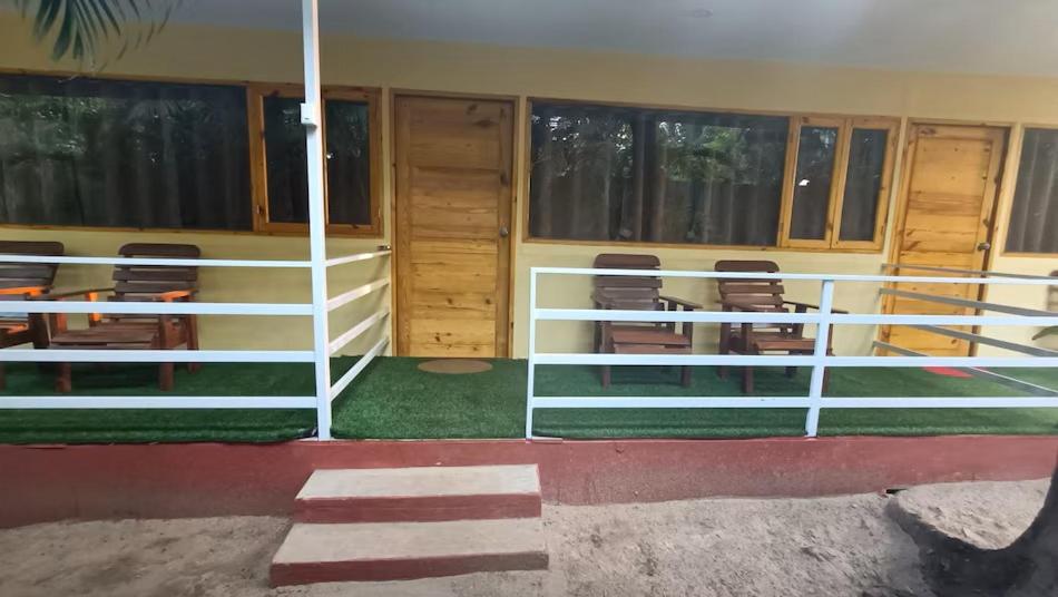 une pièce avec des balustrades, des chaises et des fenêtres blanches dans l'établissement Sea Front Beach Huts, à Patnem