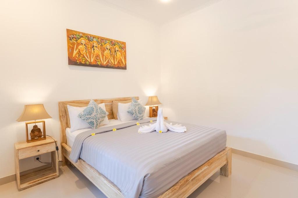 a bedroom with a white bed with a bow on it at Wayan Homestay Sanur in Sanur