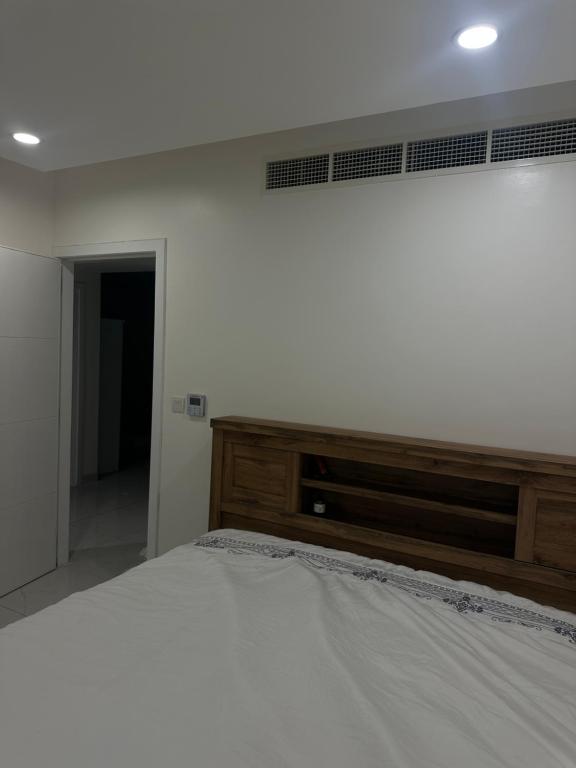 a bedroom with a white bed with a wooden headboard at Sea and lake view apartment in Muscat