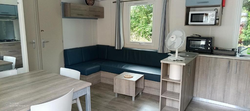 a living room with a blue couch and a table at Mobilhome Oléron in Les Sables Vignier