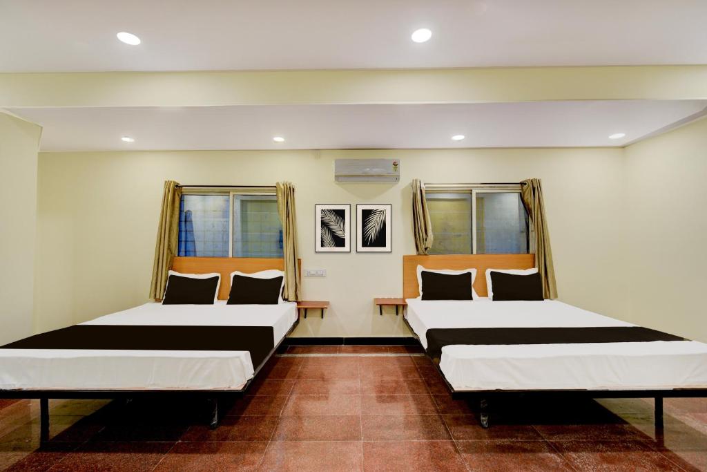 Dos camas en una habitación con dos ventanas. en Hotel O SVR Grand Inn, en Surūrnagar