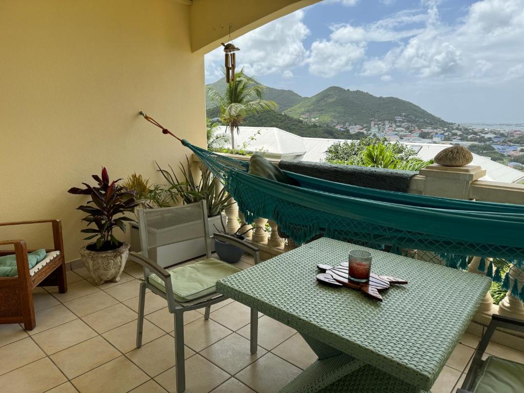 a room with a table and a hammock on a balcony at Le SPRITZ - Appartement d'une chambre VUE MER in Marigot