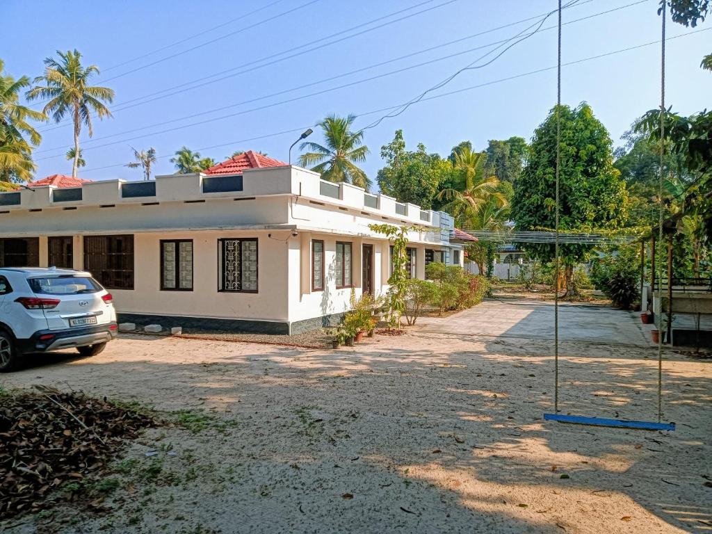 a house with a car parked in front of it at Tranquil Haven - An Ayur Escape Retreat in Kāyankulam