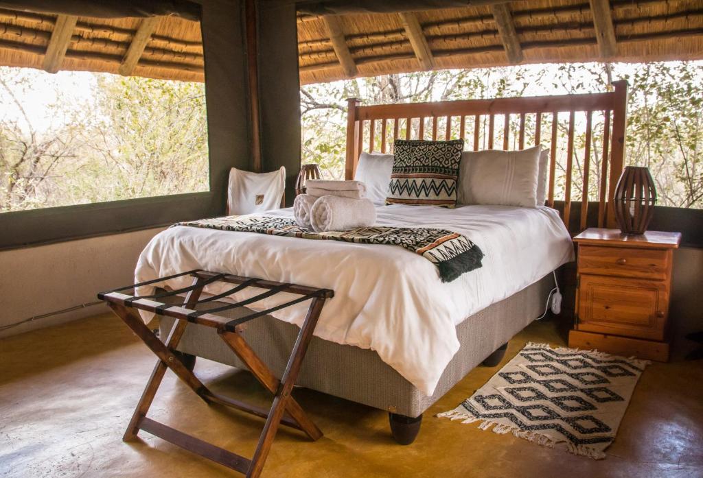 een slaapkamer met een bed, een tafel en ramen bij NIANI tented Chalet in Hoedspruit