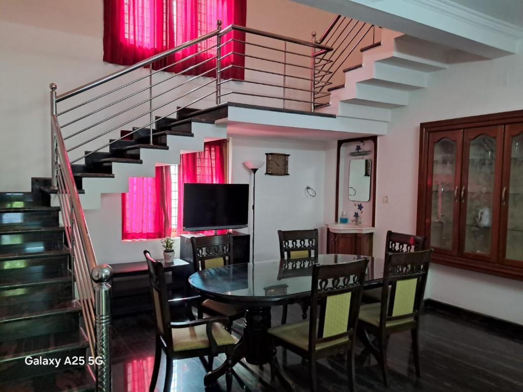 ein Esszimmer mit einem Tisch und einer Treppe in der Unterkunft 3 BHK House in Thrissur