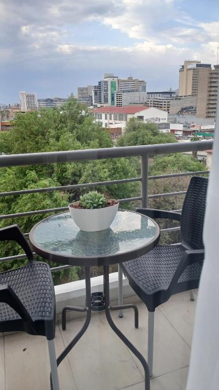 Ein Tisch und Stühle auf einem Balkon mit Blick auf eine Stadt in der Unterkunft City Duplex Trift Towers Apartment in Windhoek