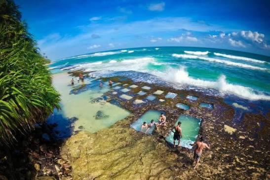 um grupo de pessoas em pé na beira de uma praia em Coco Breeze Villa em Talpe