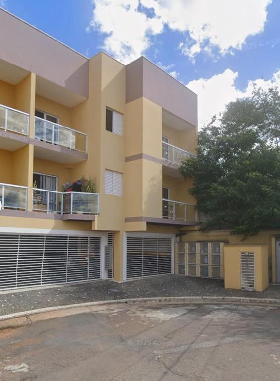 a large yellow building with a tree in front of it at Lindo Apartamento em condomínio in Itatiba