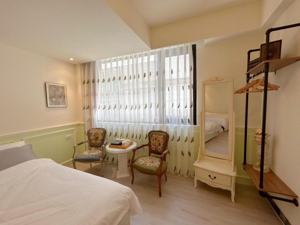 Un dormitorio con una cama y dos sillas y un espejo. en 巴洛克文旅 #海安藝術街#神農街住宿#花園夜市民宿推薦, en Tainan