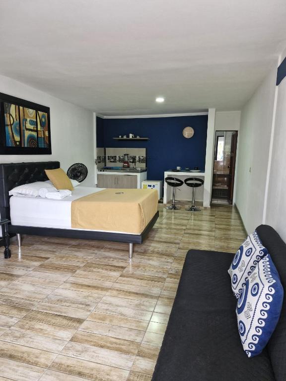 a bedroom with a large bed and a kitchen at Hermoso aparta estudio in Zarzal