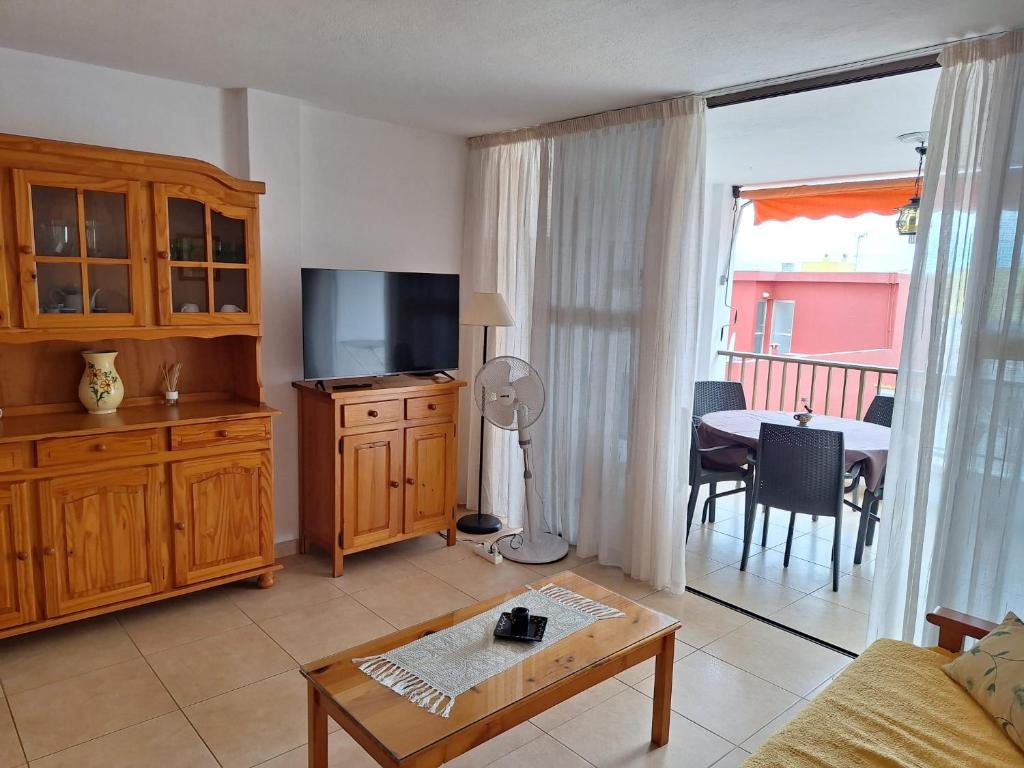 Una sala de estar con un televisor y una mesa con un comedor. en Gloria Apartament, en Puerto Naos
