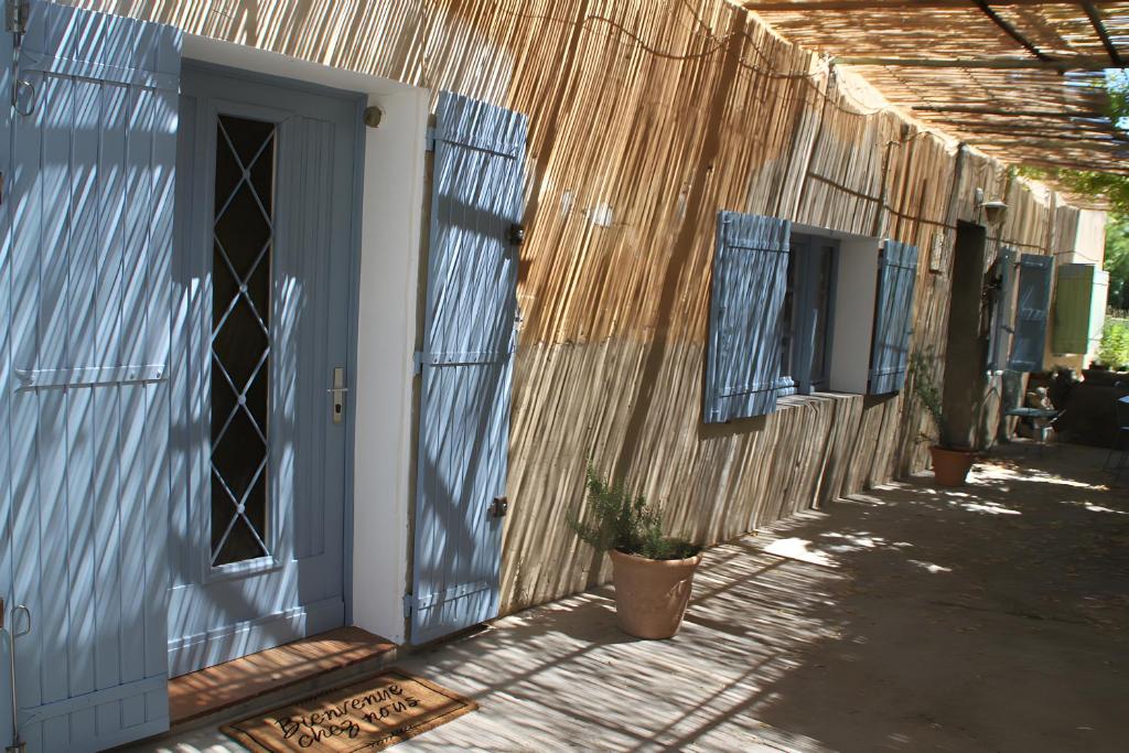 a house with a blue door and a potted plant at Le Mas Des Glycines in Les Vignères