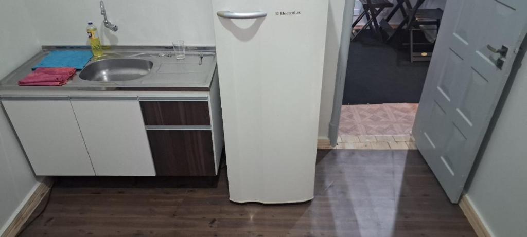 einen weißen Kühlschrank in einer Küche neben einer Spüle in der Unterkunft Pequeno quarto no coração de Curitiba in Curitiba