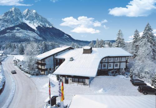 un bâtiment enneigé avec une montagne enneigée dans l'établissement Hotel Quellenhof, à Grainau