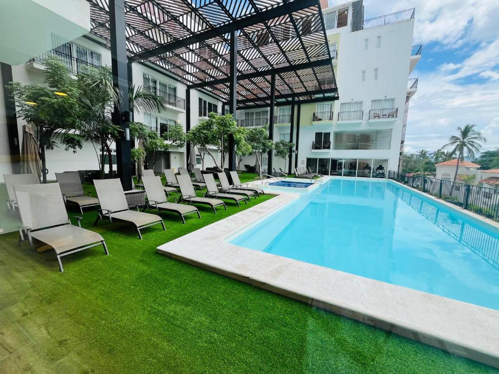 a swimming pool with lounge chairs next to a building at Life Bucerías, Modern Studio Near the Beach in Bucerías
