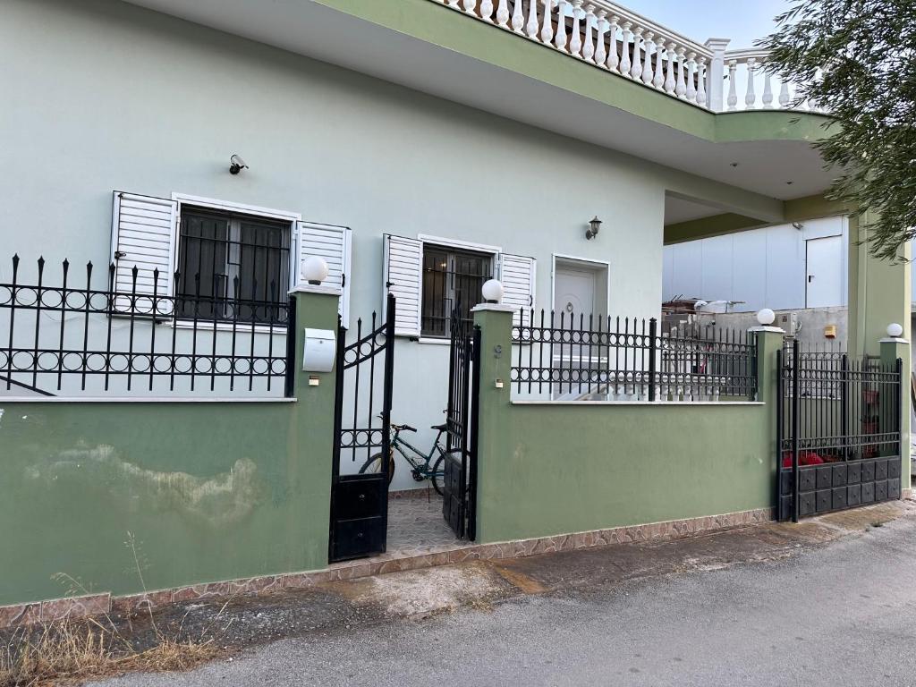 ein weiß-grünes Haus mit Toren und Zäunen in der Unterkunft Elena's Guest House in Aiándion