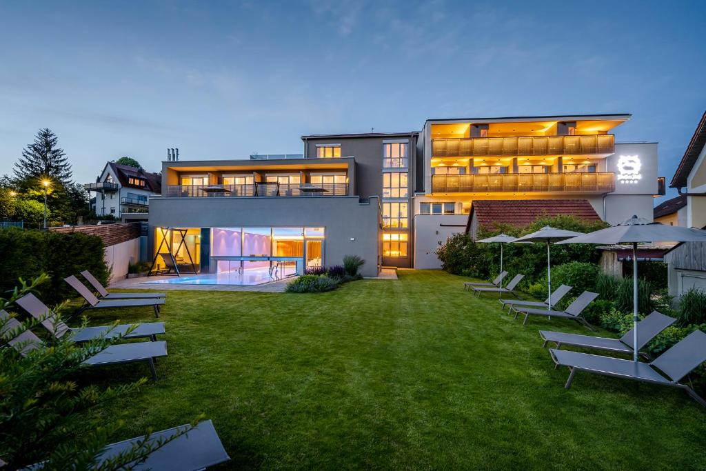 Una vista exterior de una casa con sillas de jardín y sombrillas. en Landhotel Weißes Roß, en Illschwang