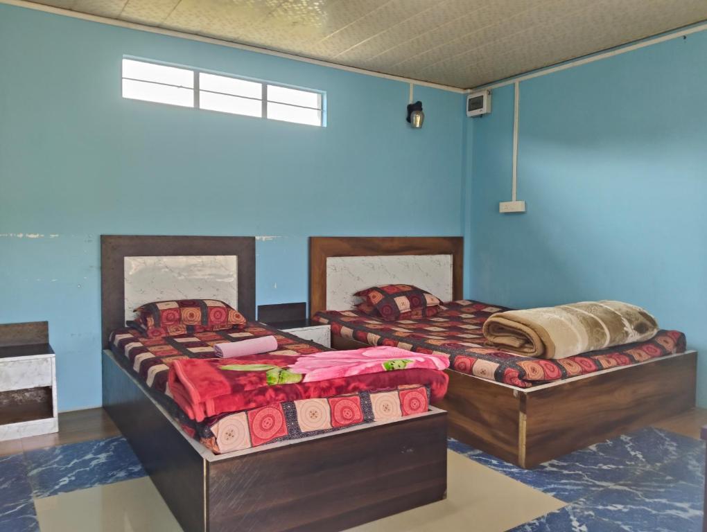 deux lits dans une chambre aux murs bleus dans l'établissement DADA TOURIST COTTAGE & Camping site, à Cherrapunji