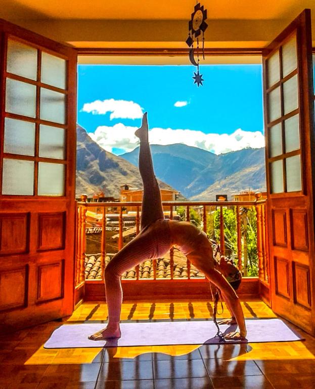 a woman doing a yoga pose in front of a window at Aqui y Ahora in Pisac
