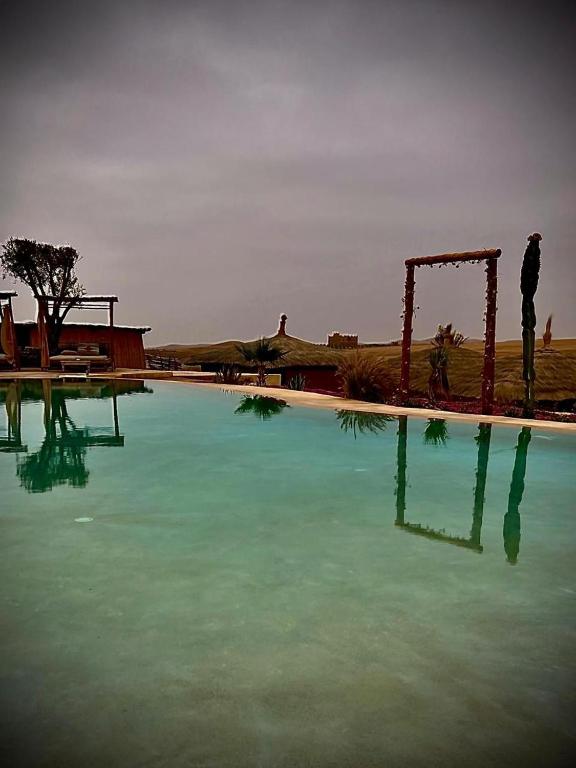 a large pool of blue water next to at Les Bedouins Agafay in Oulad Akkou