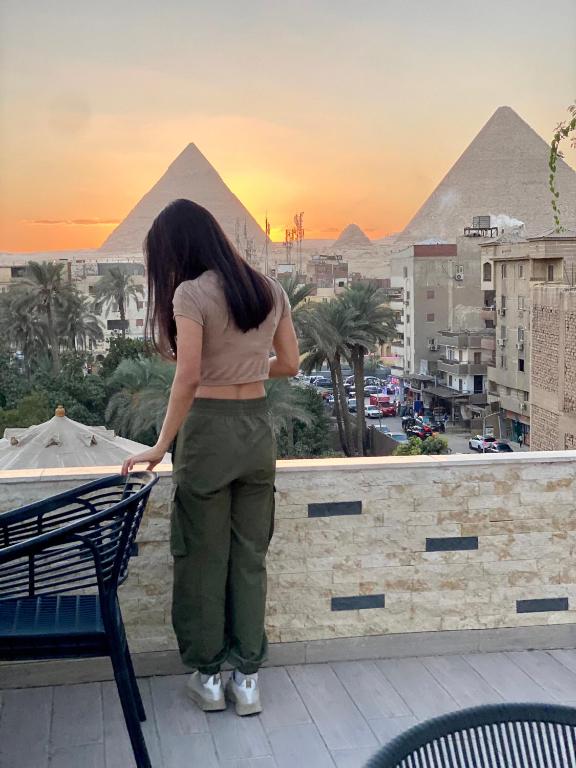 a woman standing on a ledge looking at the pyramids at Velora Pyramids Hotel in Cairo
