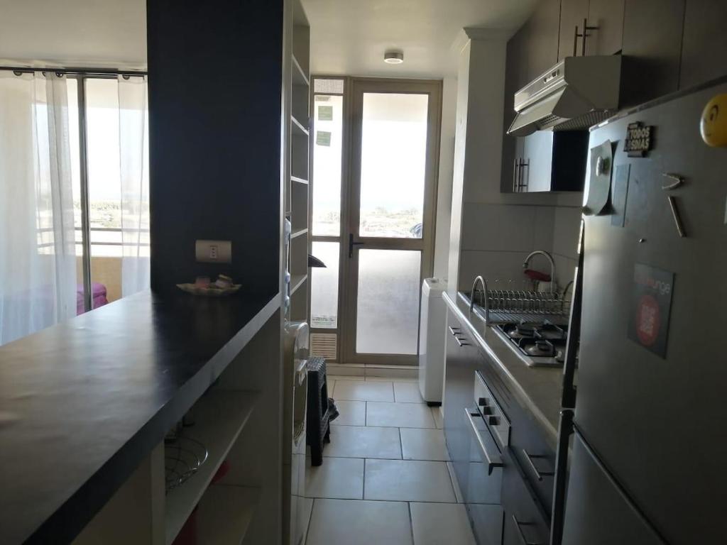 a kitchen with a refrigerator and a counter top at Apartamento amoblado de 3 dormitorios con parking incluido in Arica