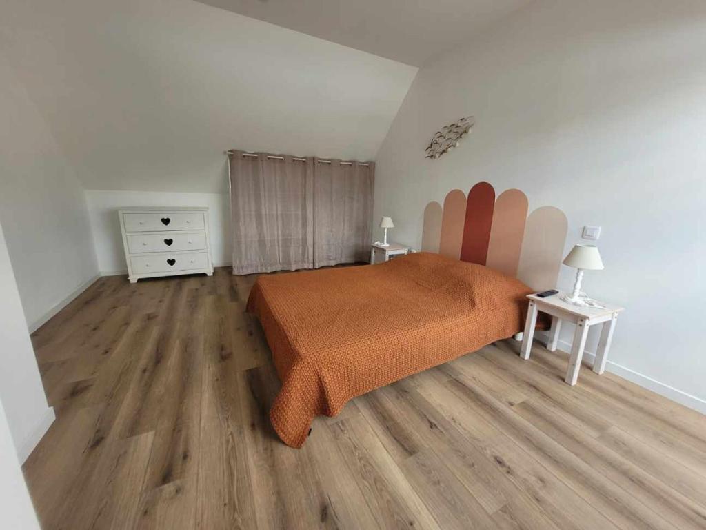 a bedroom with a bed with an orange blanket at Petite maison de campagne avec poêle à bois, 20 mn des plages in Bréhand