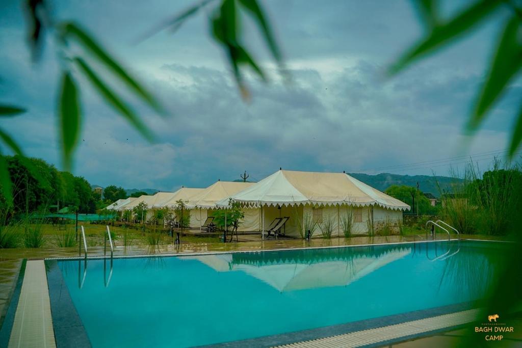una gran carpa junto a una piscina en Baagh Dwar Camp & Resort, en Khilchīpur