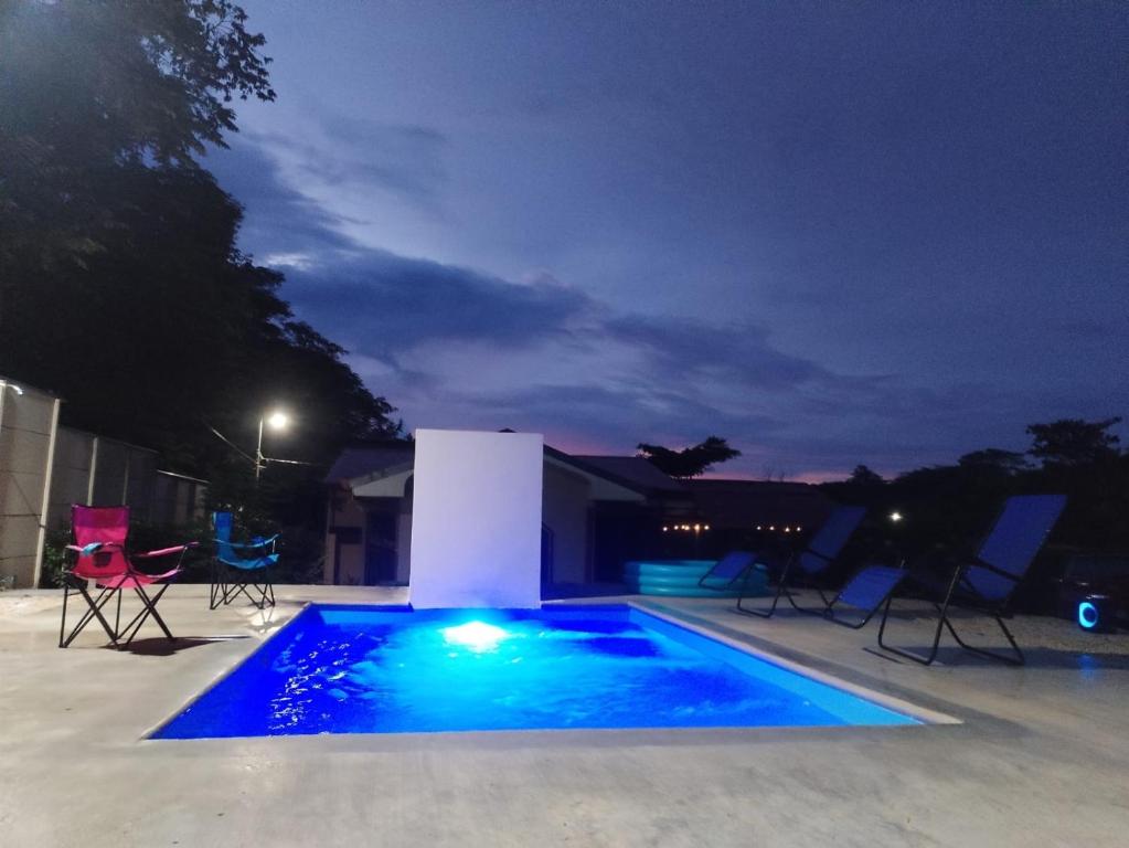 a swimming pool at night with chairs around it at Casa Chika Playa Grande Guanacaste 2 in Cuajiniquil