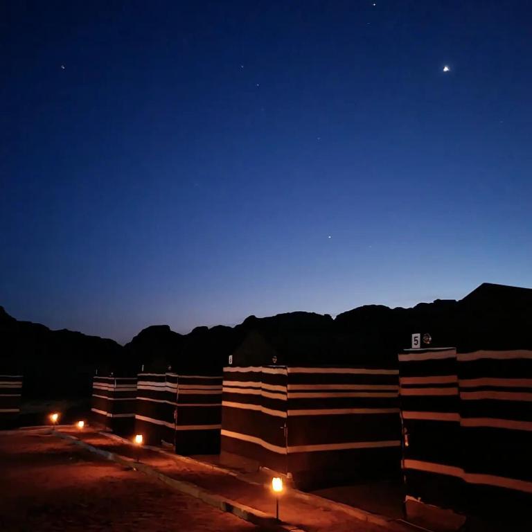 a row of buildings at night with a blue sky at Sunrise Magic Camp in Wadi Rum