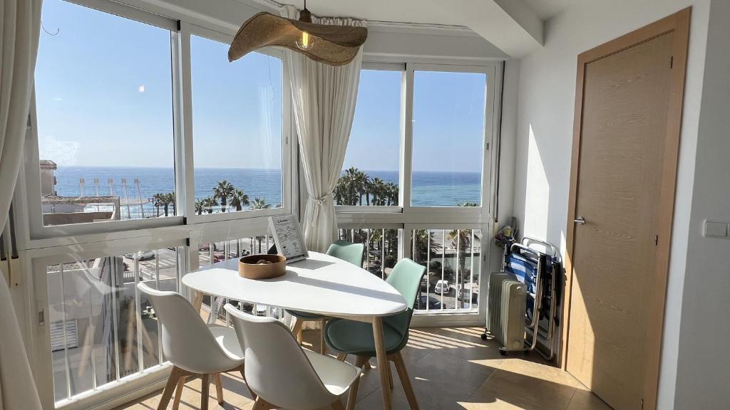 a white table and chairs in a room with windows at Wake up to the Oceanfront Panoramic 180º Beachview Torrox-Costa Ruselo R408 ONLY ADULTS in Torrox Costa