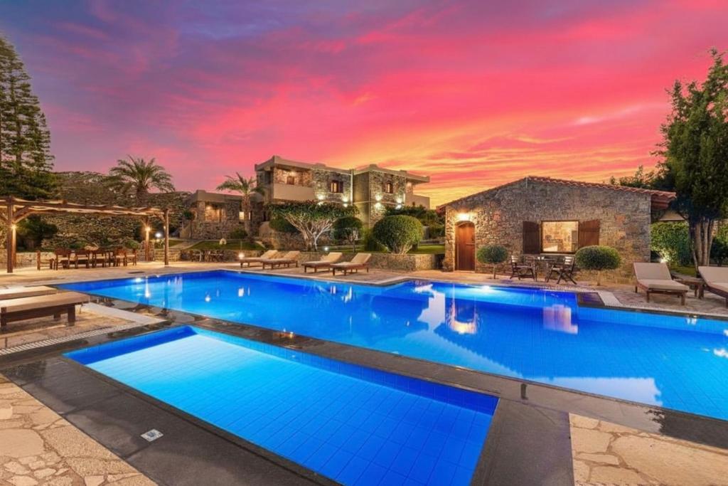 a pool in front of a house with a sunset at Nectar Luxury Apartments in Sitia