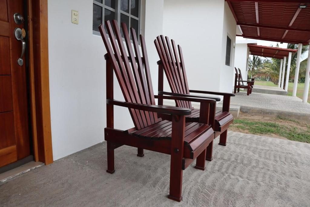 deux chaises en bois assises sur le porche d'une maison dans l'établissement Villa Regina en Villas Camino Real cerca de las dunas de Chachalacas, à Ursulo Galván