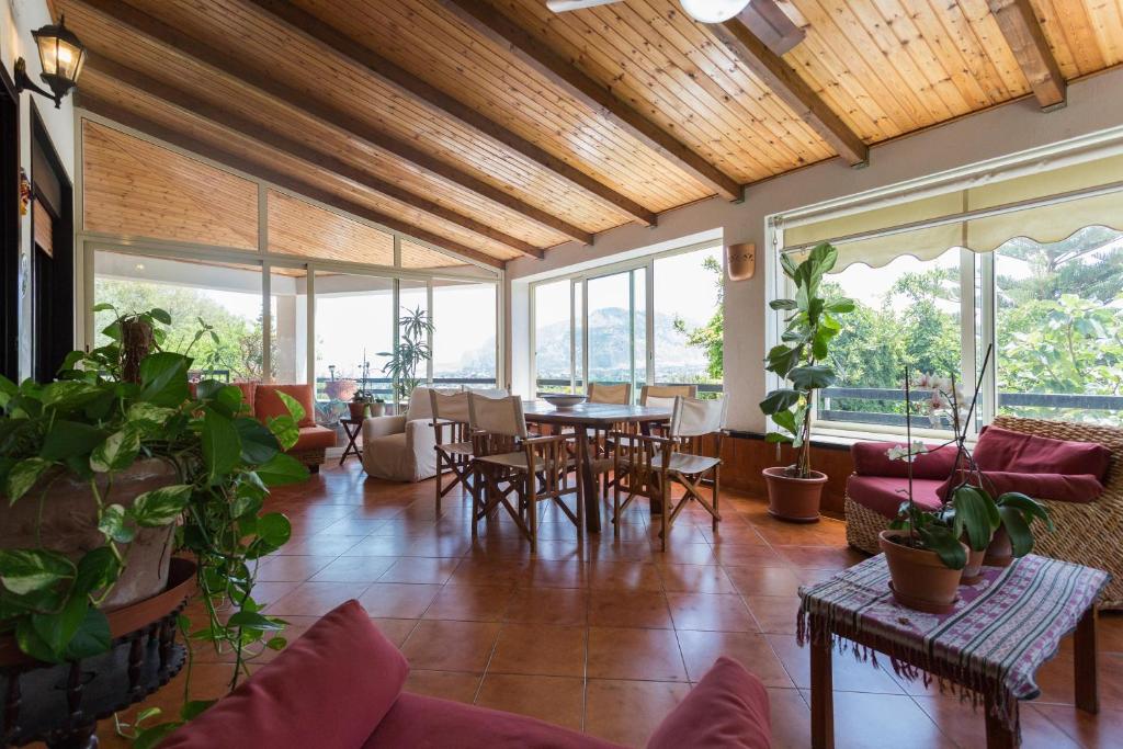 un soggiorno con tavoli, sedie e finestre di Villa Soliva a Mondello